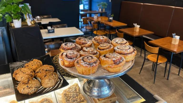 Cinnamon scrolls and scones on the cafe counter, with seating beyond