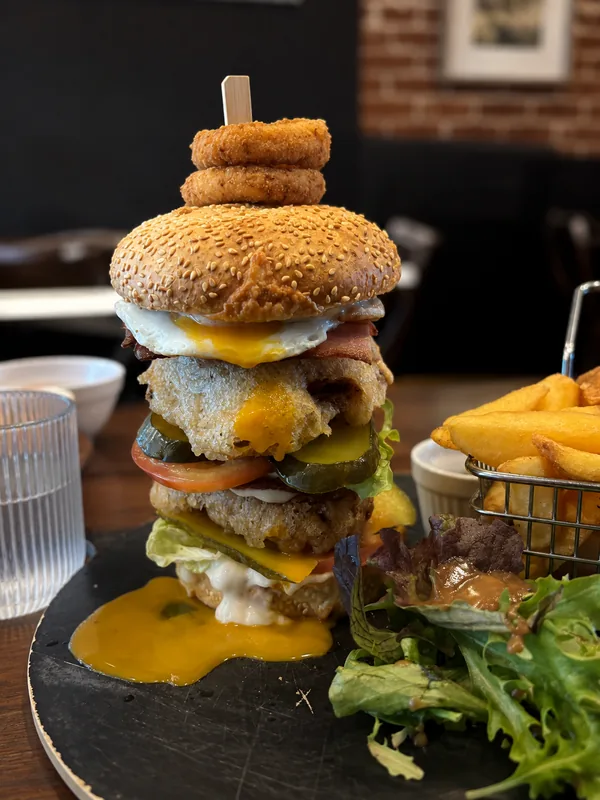 A towering burger with fries at Sweet Lili’s