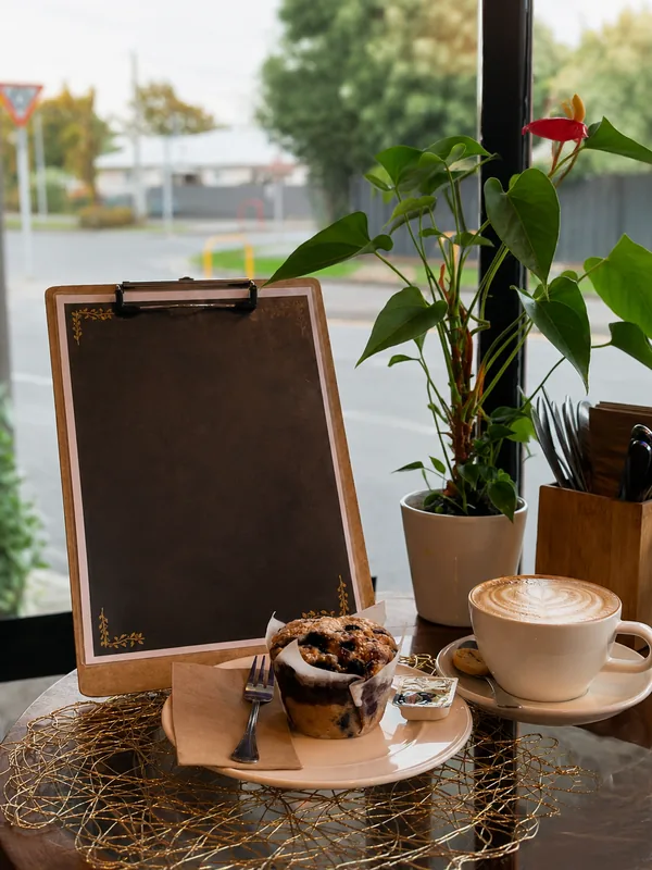 Breakfast menu, coffee and a blueberry muffin by the window